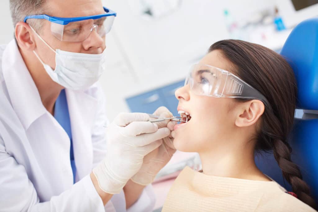 The dentist is evaluating dental health before the gum grafting procedure.