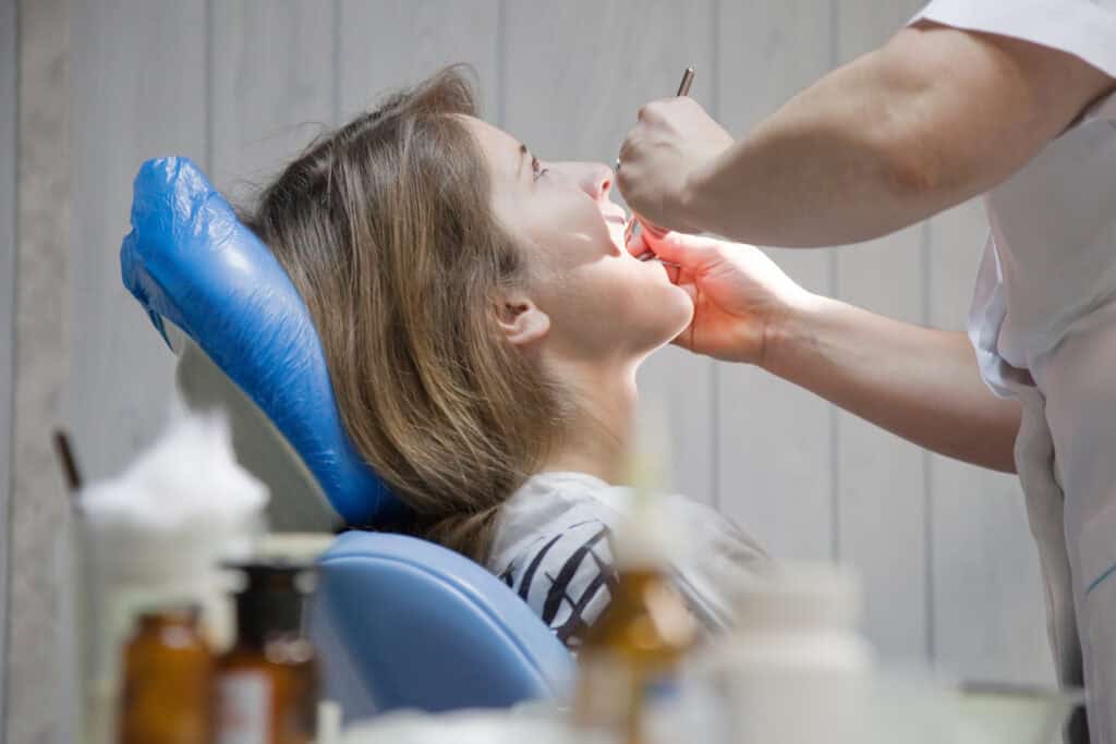 Teeneger girl during inspection of oral cavity with help of hook and mirror