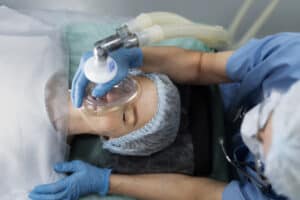 Patient calmly undergoing administration of General Anesthesia by an anesthetist in a medical setting, ensuring comfort during surgery.