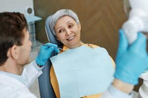 Smiling senior patient discussing full arch dental implant options with her oral surgeon
